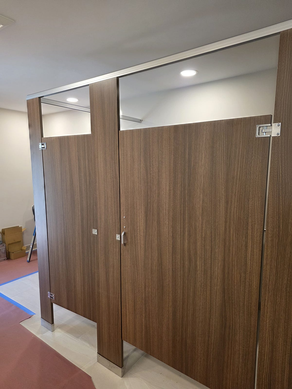 Plastic laminate bathroom partitions with a wood-grain finish in a corporate office restroom