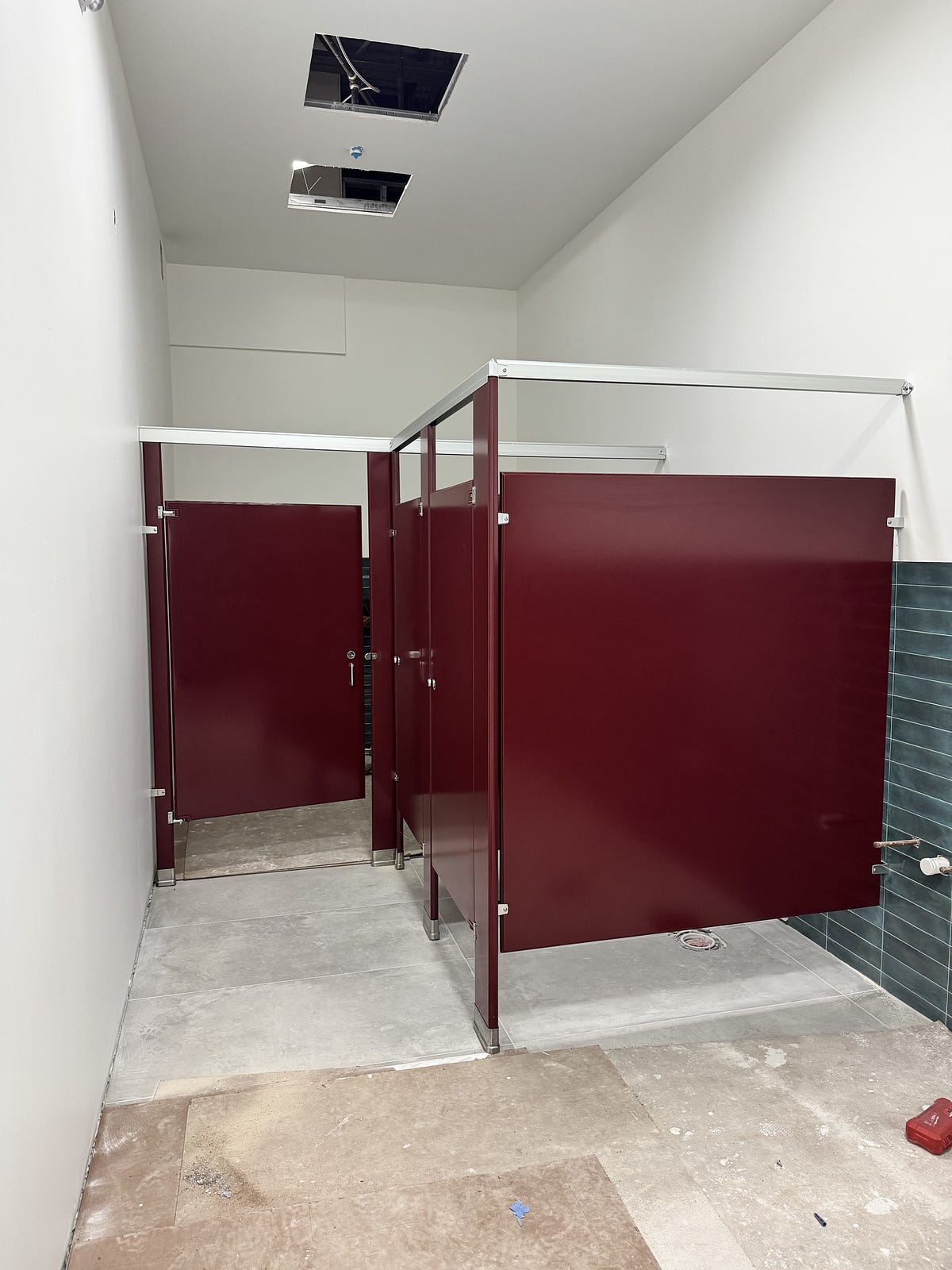 Powder coated steel commercial bathroom partitions installed in a public restroom